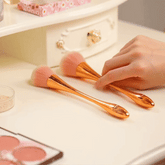Cosmetic brush with rose gold fan design on white background