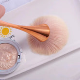 Makeup brush applying highlighter to cheekbone